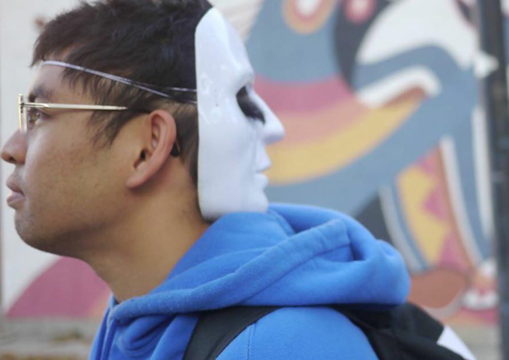 Side photo with white mask in front of Jack Beardy Mural in North End